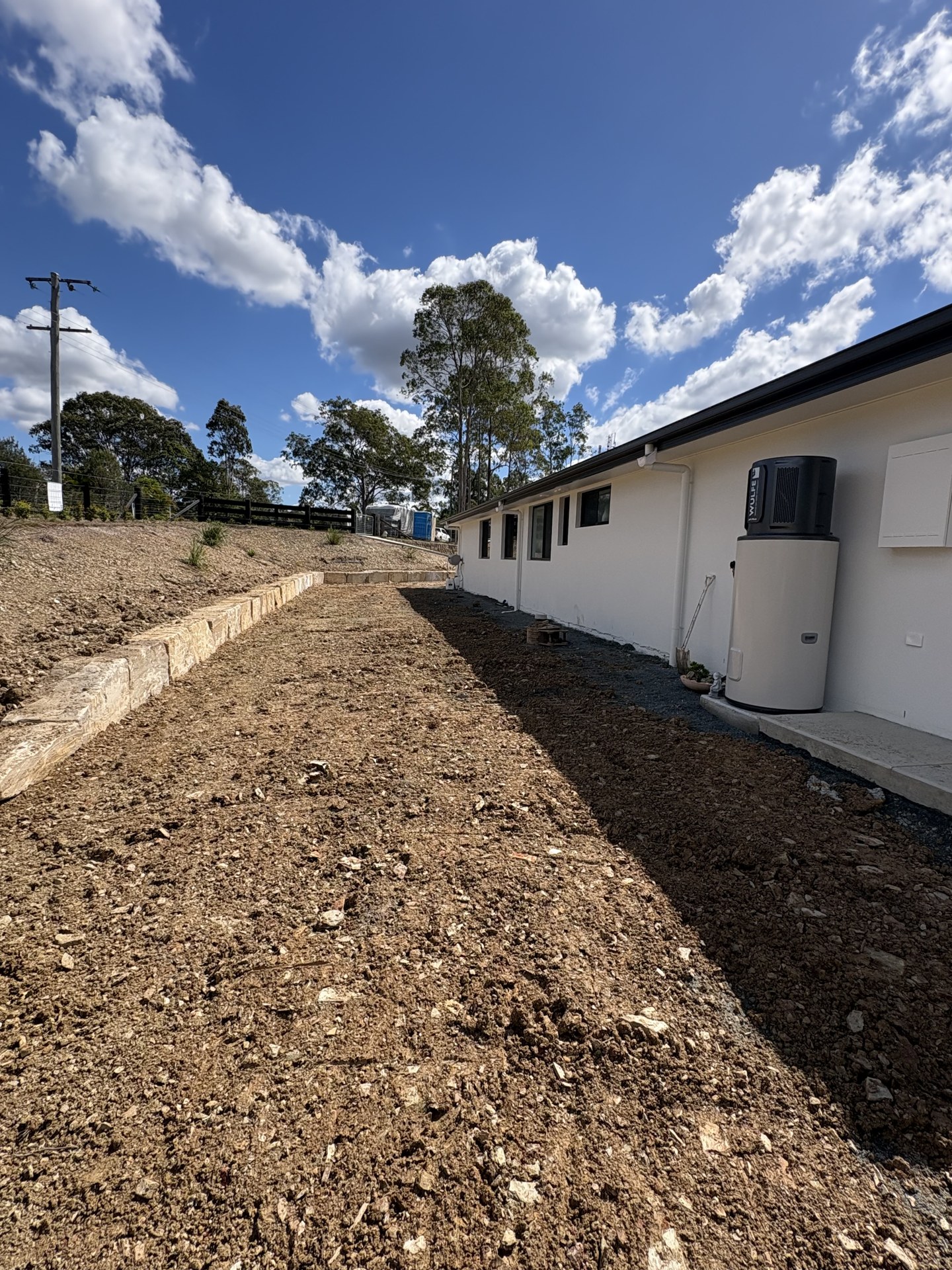 Sandstone block retaining wall holding a bank beside a new home near Gympie QLD