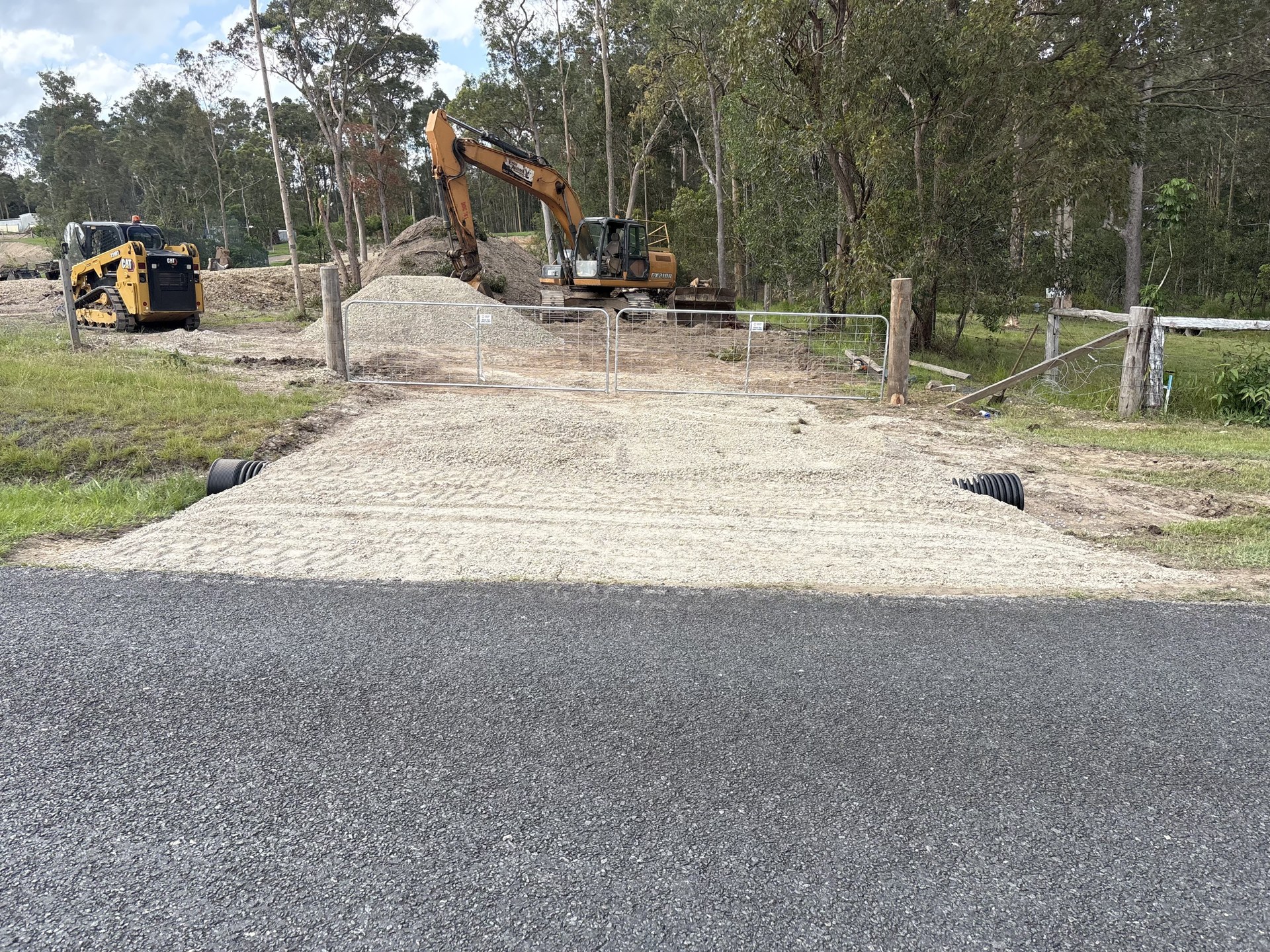 Gravel driveway running through new steel farm gates on a rural block near Gympie QLD