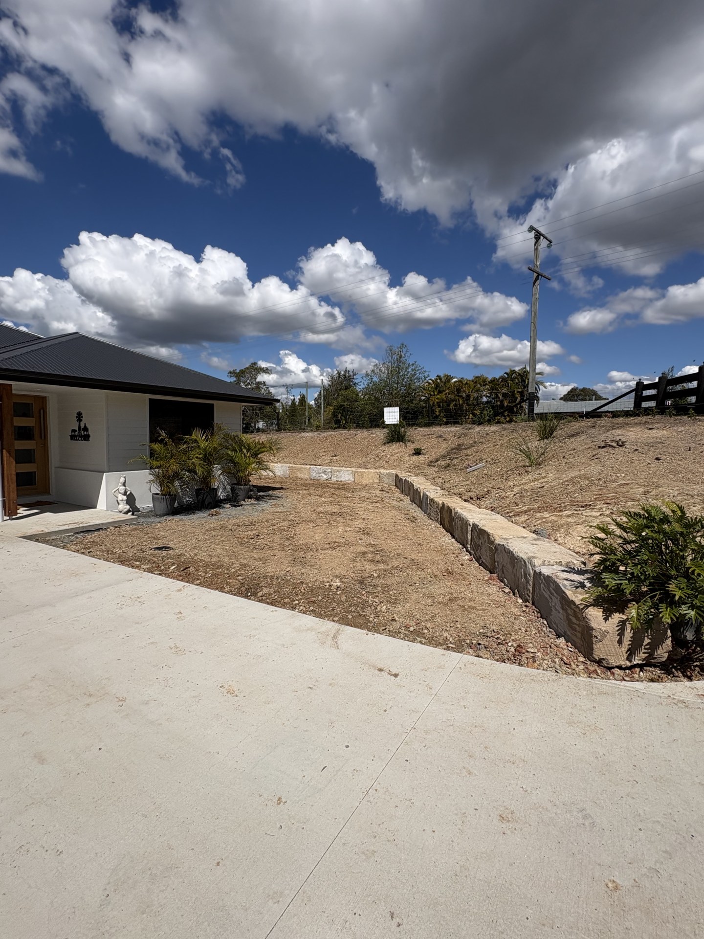 Sandstone retaining wall and graded garden bed beside a concrete driveway near Gympie QLD