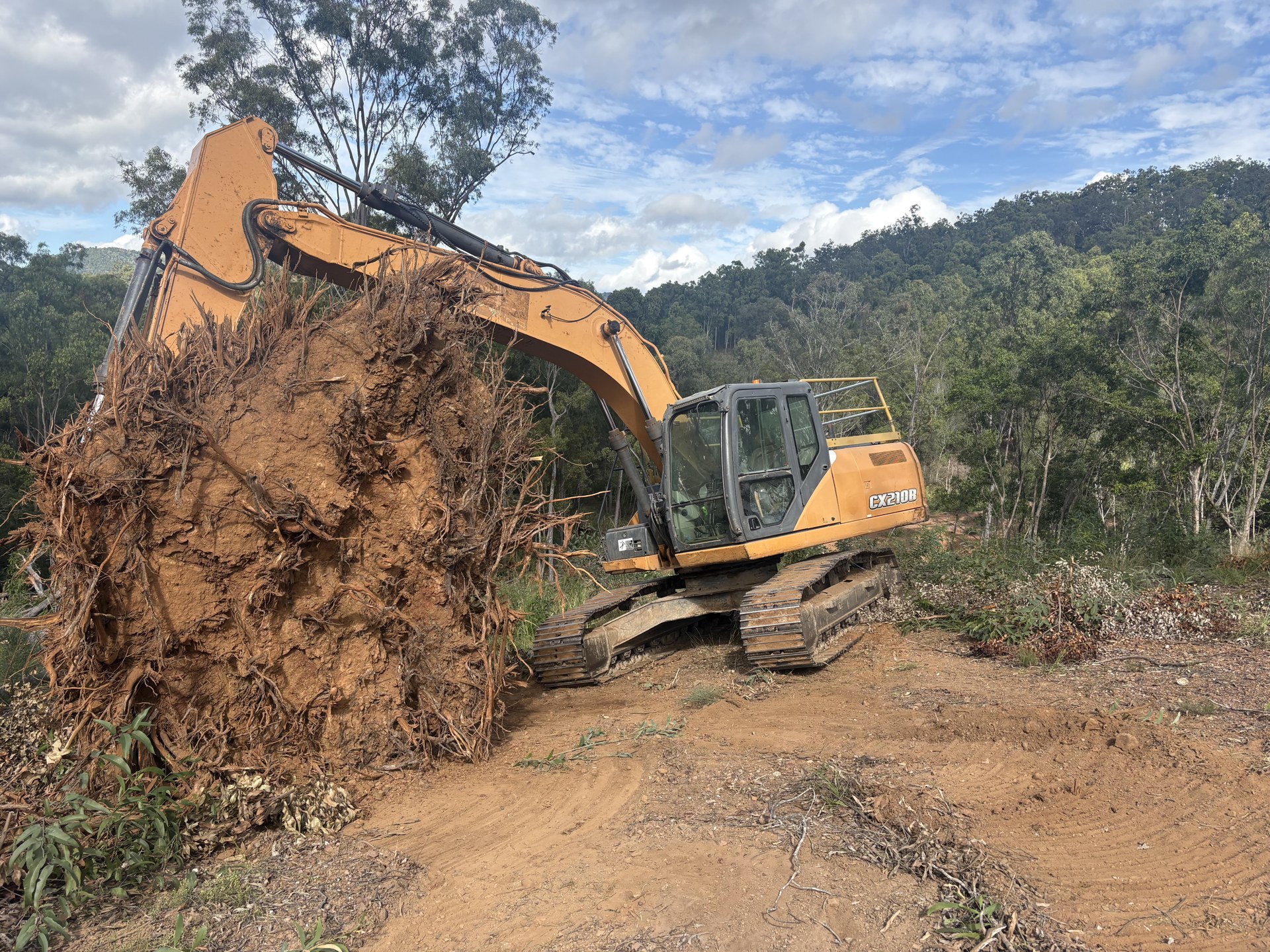 Excavator clearing timber and shaping ground during earthworks at Glastonbury QLD