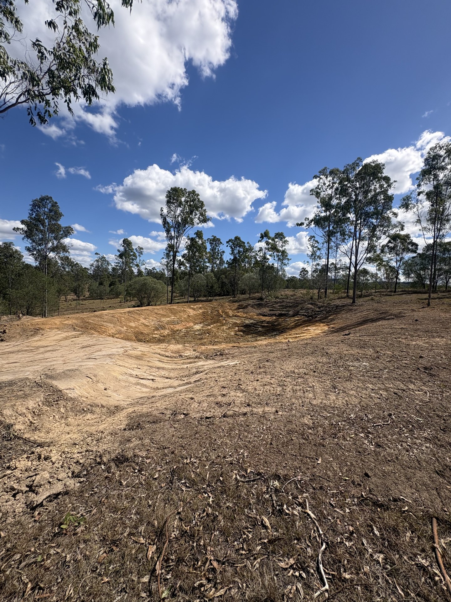 Finished dam with graded batters and spoil spread on site near Gympie QLD