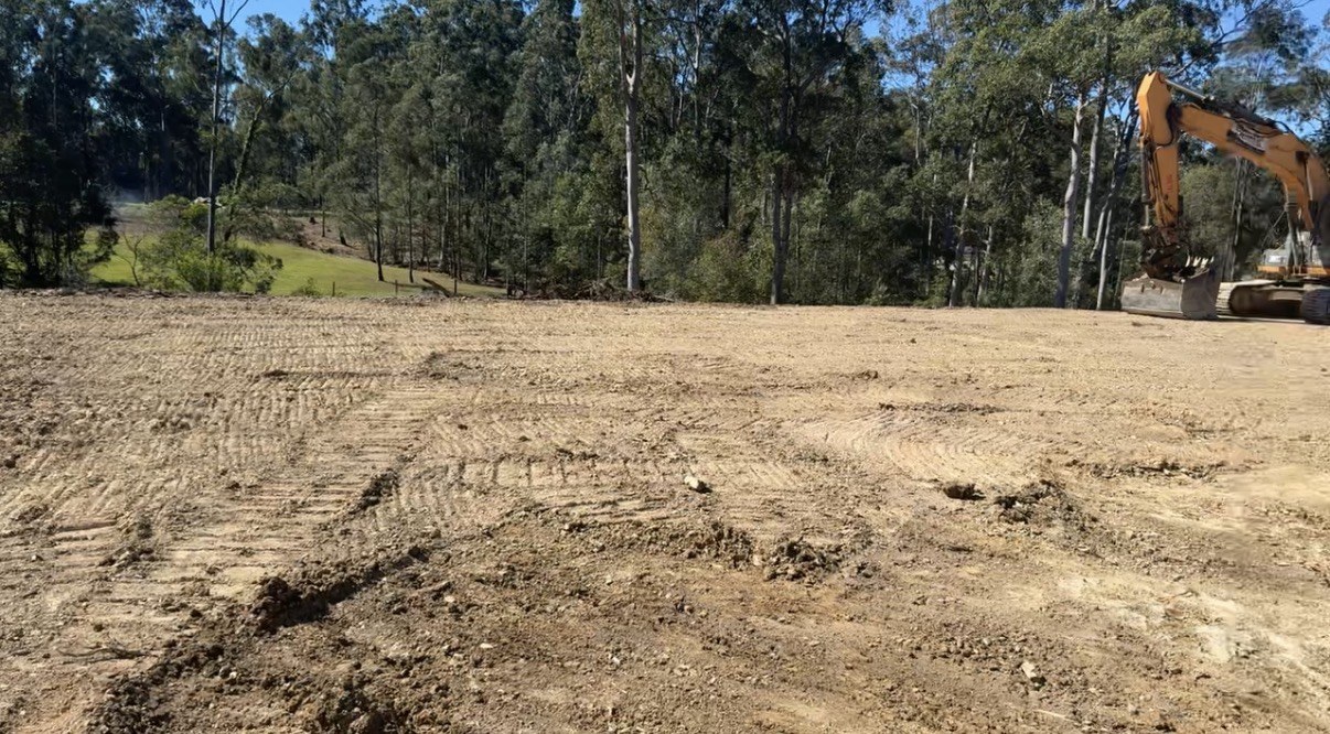 Level cut yard area beside bushland with excavator on site near Gympie QLD