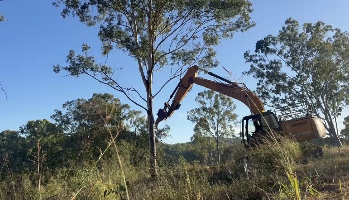 Excavator clearing timber and topsoil ahead of a site cut at Glastonbury QLD